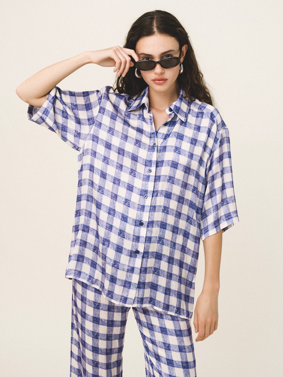 Person wearing a blue and white checkered outfit on a beige background