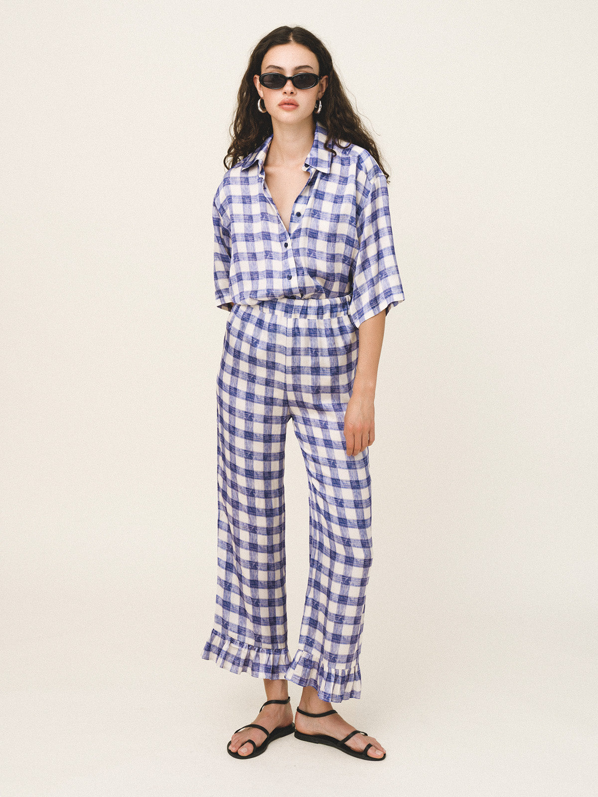Woman wearing a blue and white checkered outfit on a plain background