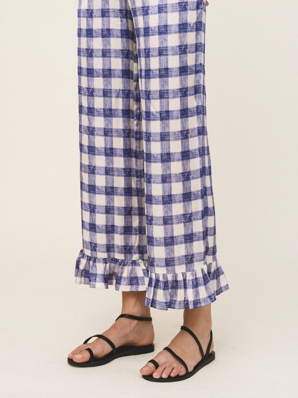 Blue and white checkered pants with ruffled bottom hem on a beige background