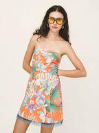 Woman wearing a strapless floral dress with colorful pattern on a plain background