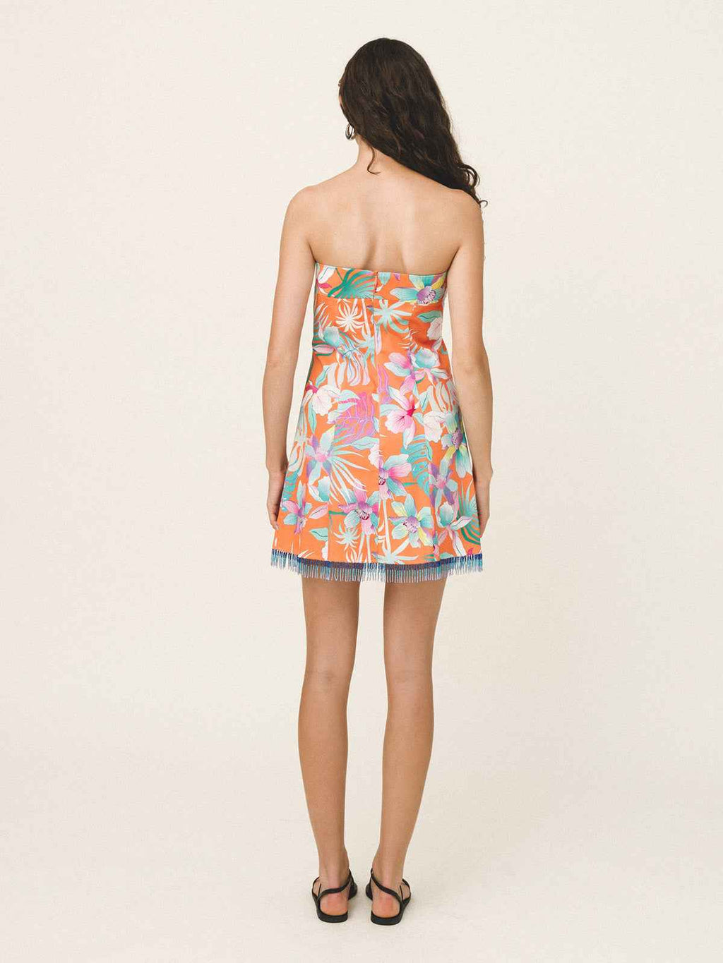 Woman wearing a strapless floral dress on a plain background