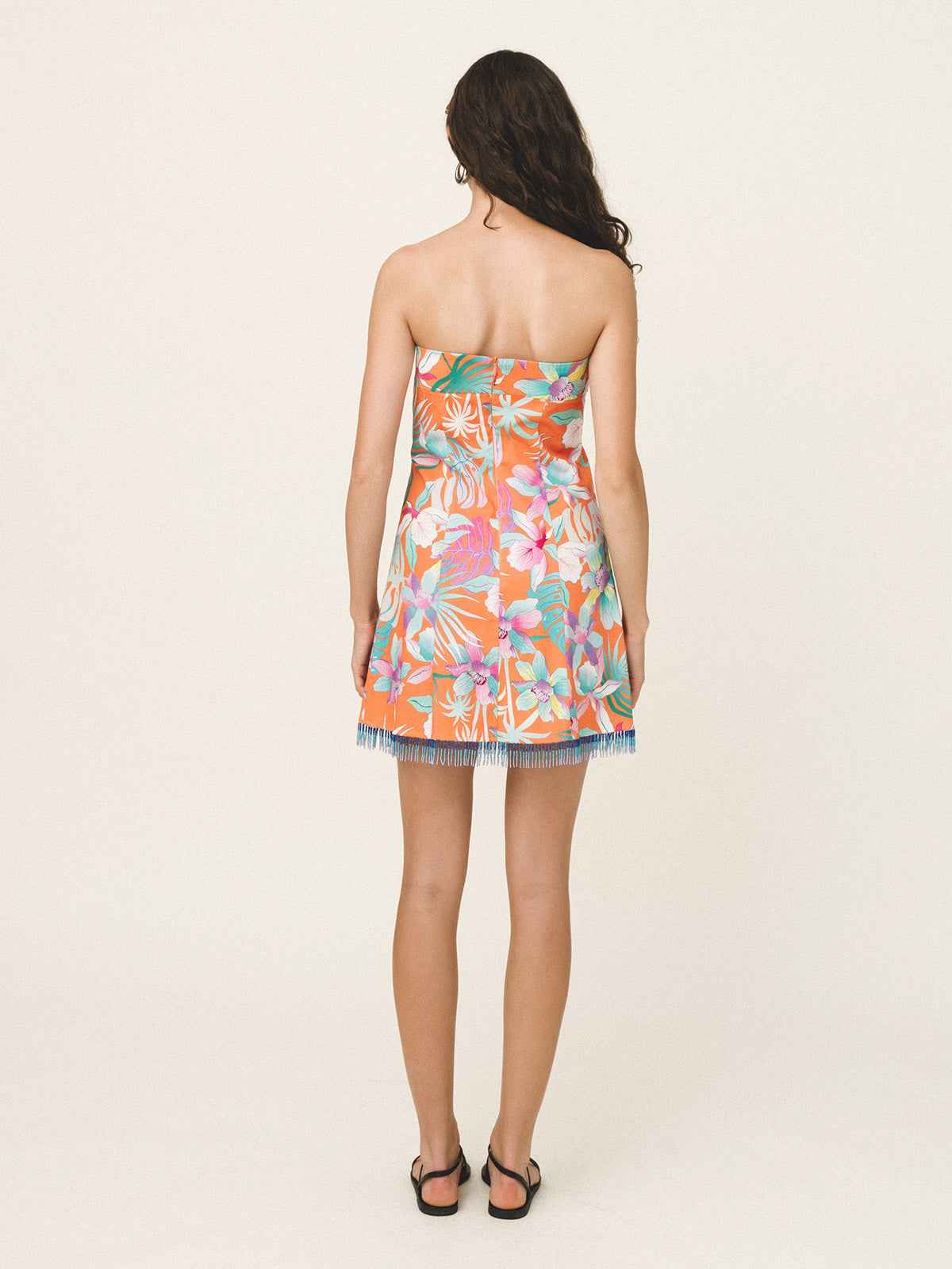 Woman wearing a strapless floral dress on a plain background