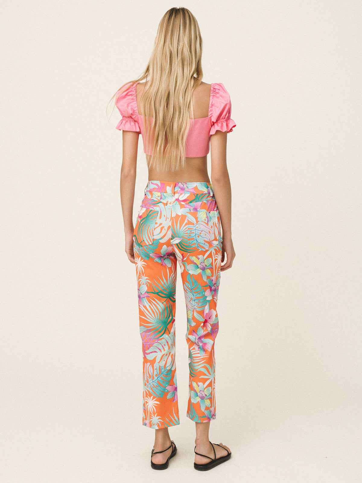 Woman wearing a colorful tropical print outfit on a white background