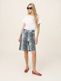 Woman wearing a white t-shirt and floral skirt with red shoes on a white background