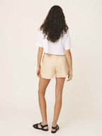 Woman wearing a white top and beige shorts on a plain background