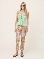Woman wearing a light green top and colorful floral pants on a white background