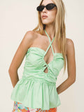 Woman wearing a light green halter top with floral shorts on a plain background