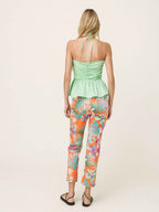 Woman wearing a green top and colorful tropical pants on a white background
