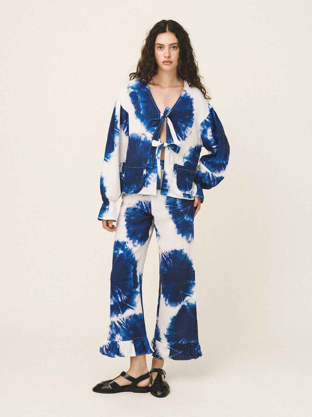 Woman wearing a blue and white tie-dye outfit on a plain background
