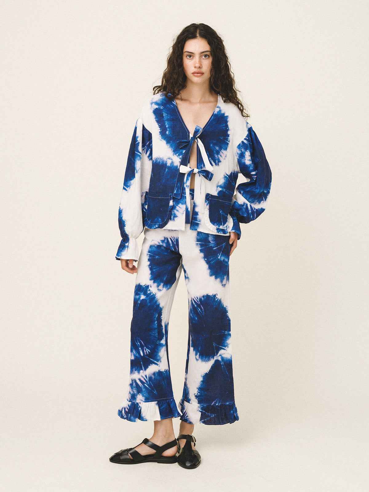 Woman wearing a blue and white tie-dye outfit on a plain background