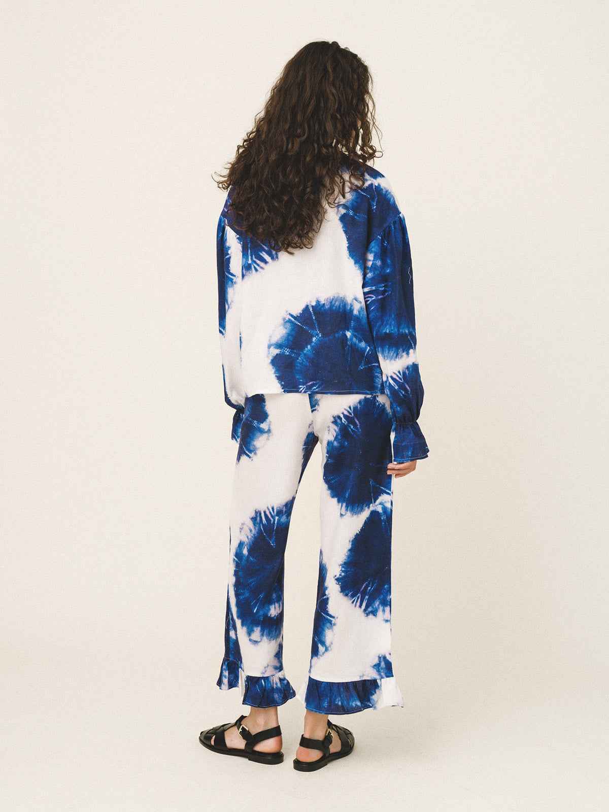 Person wearing a blue and white tie-dye outfit on a plain background