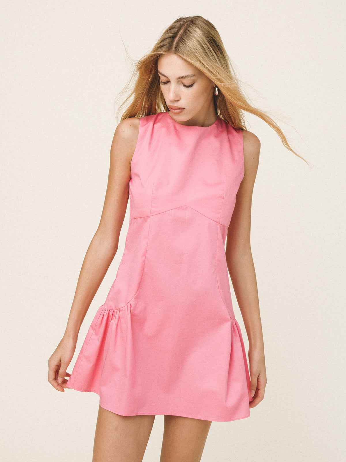 Woman wearing a pink dress against a plain background
