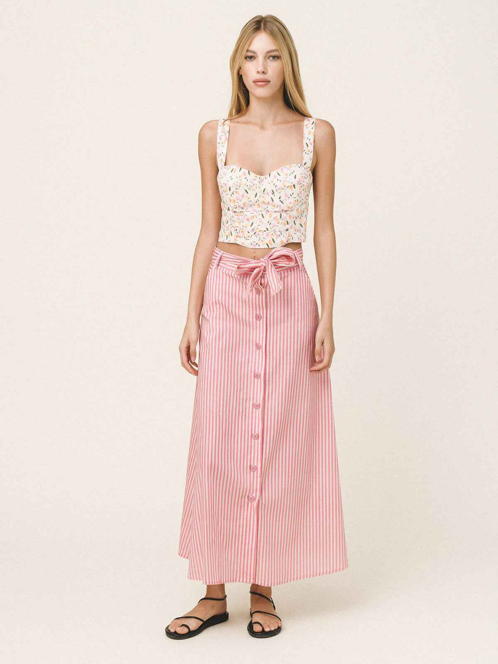 Woman wearing a white lace top and pink striped skirt on a white background