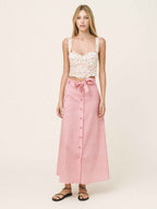 Woman wearing a white lace top and pink striped skirt on a white background