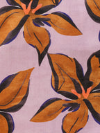 A close-up of a floral fabric pattern featuring large orange-brown flowers with dark navy and black outlines on a light lavender background.