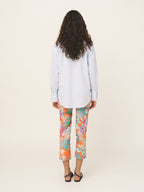 Woman wearing a light blue shirt and colorful floral pants on a white background
