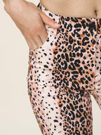 Leopard print pants worn by a person on a beige background