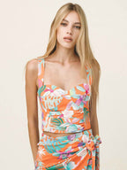 Woman wearing a colorful floral dress against a plain background