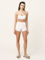 Woman wearing a white top and shorts set on a plain background