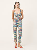 Woman wearing a patterned top and pants on a white background