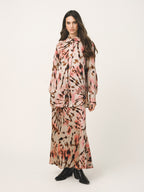 Woman wearing a long, patterned dress with a white background