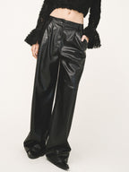 Person wearing black shiny pants on a white background