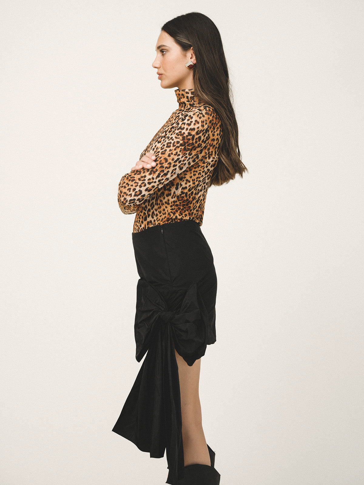 Woman wearing a leopard print top and black skirt on a white background