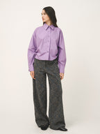 Woman wearing a purple shirt and patterned pants on a white background