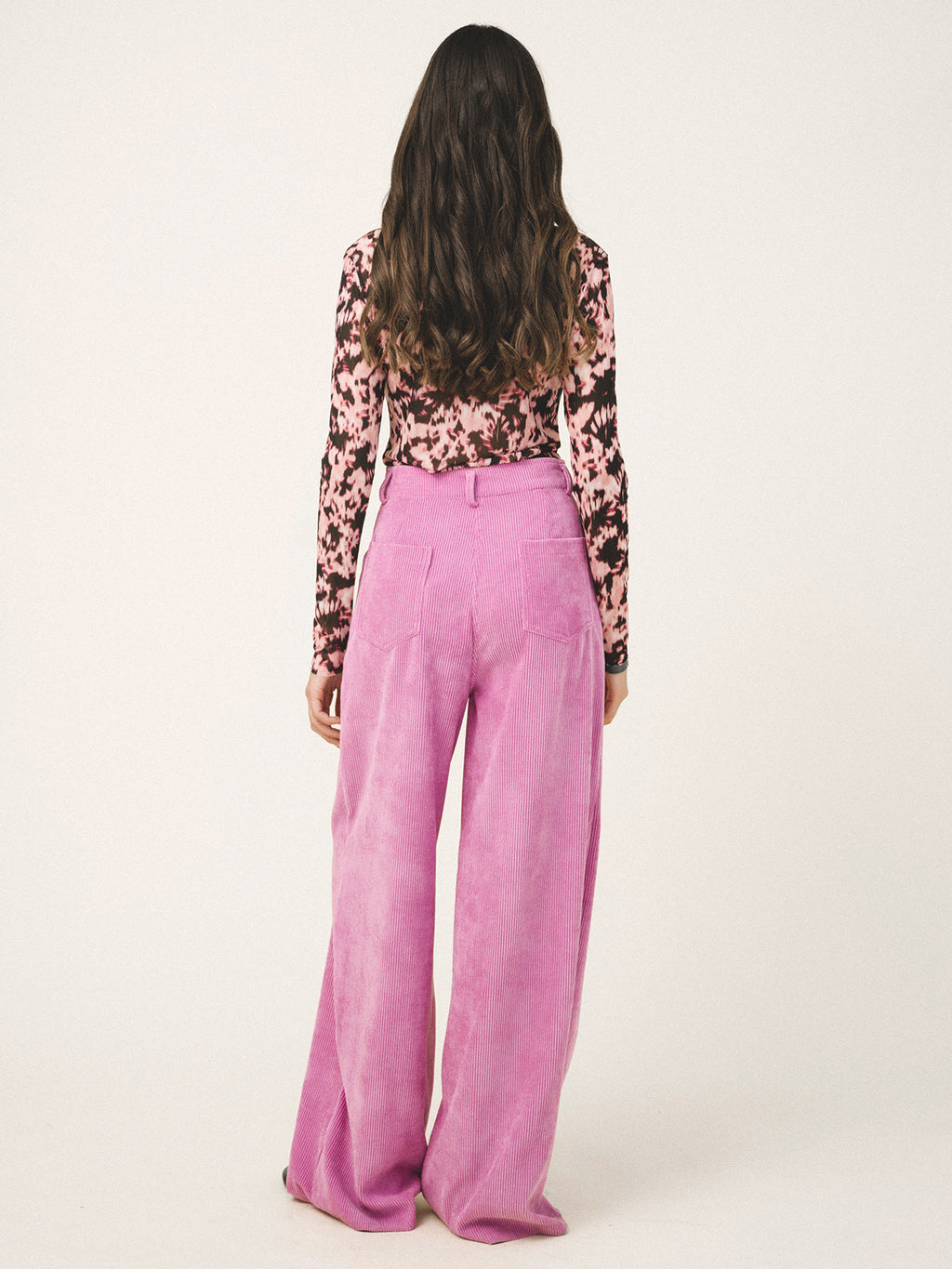 Person wearing a floral top and pink pants on a white background