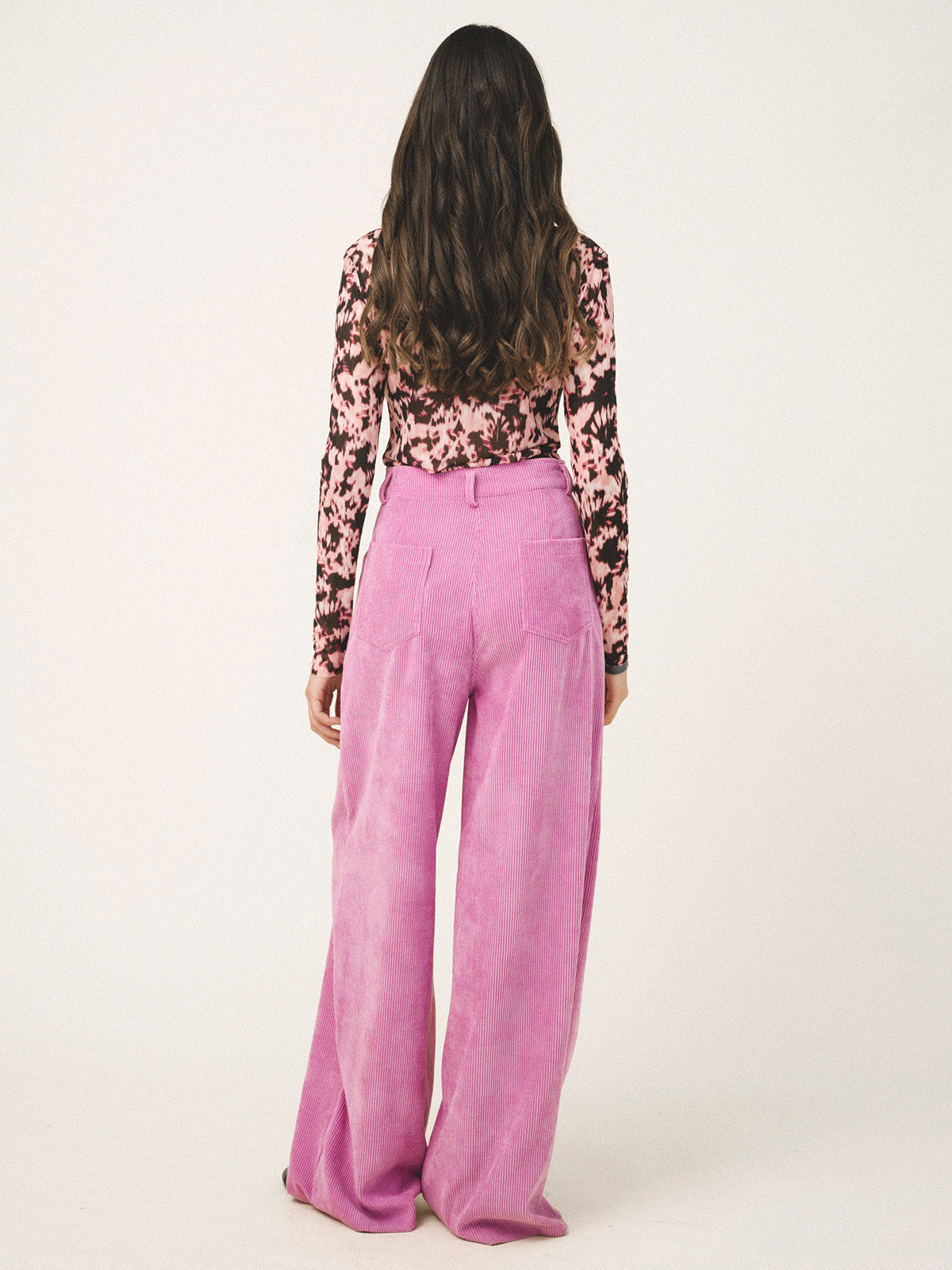 Person wearing a floral top and pink pants on a white background