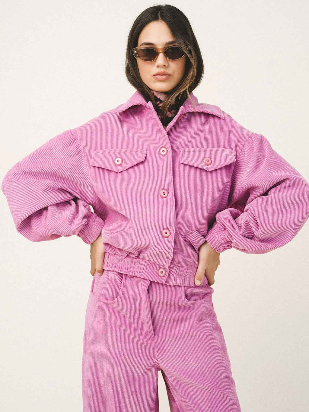 Person wearing a pink corduroy outfit on a white background
