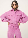 Person wearing a pink corduroy outfit on a white background