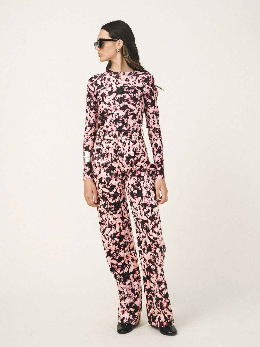 Woman wearing a pink floral jumpsuit on a white background