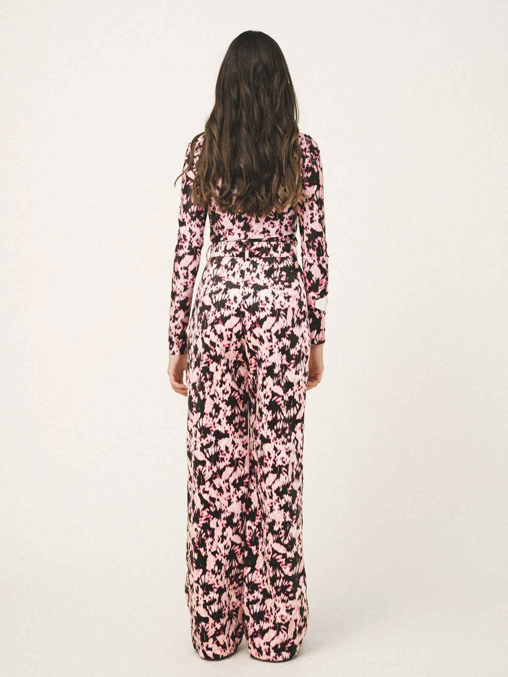 Person wearing a pink and black floral jumpsuit on a white background