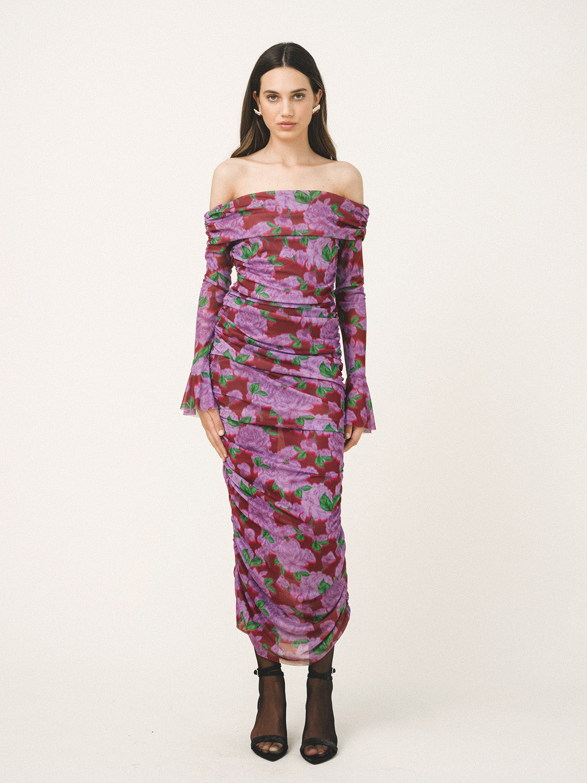 Model wearing a purple floral off-shoulder dress on a white background