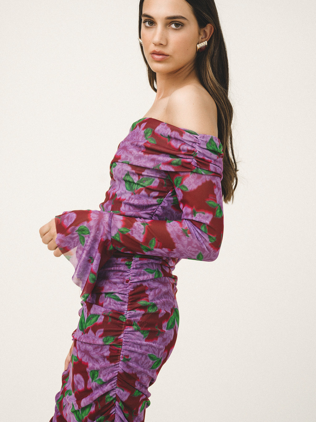 Woman wearing a purple floral off-shoulder dress on a white background