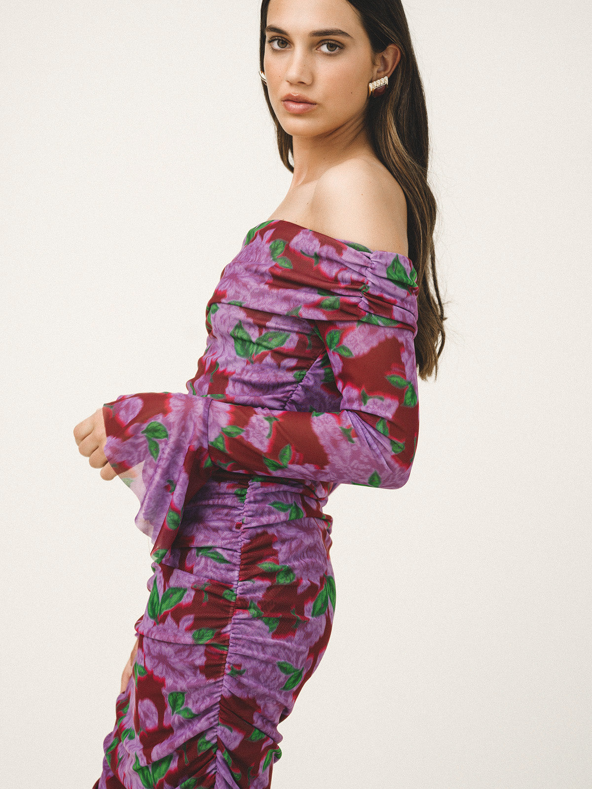 Woman wearing a purple floral off-shoulder dress on a white background