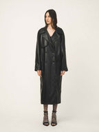 Woman wearing a long black leather coat on a white background