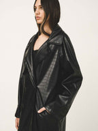 Person wearing a black leather coat on a plain background
