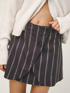 Person wearing a black pinstripe skirt with a white cardigan