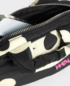 Black and white polka dot bag with a pink logo on a light gray background