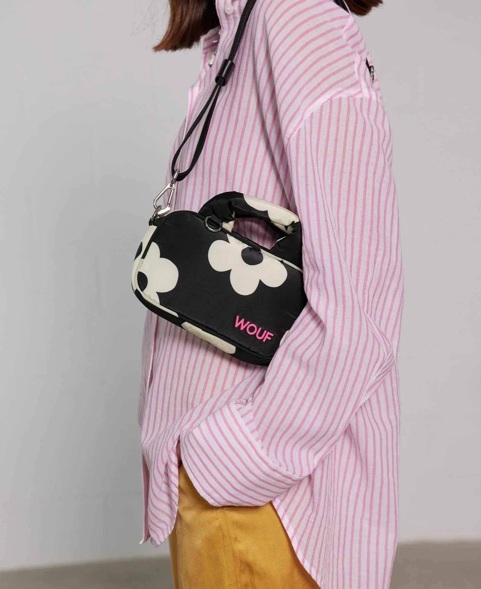Person wearing a pink striped shirt with a black and white floral-patterned bag.
