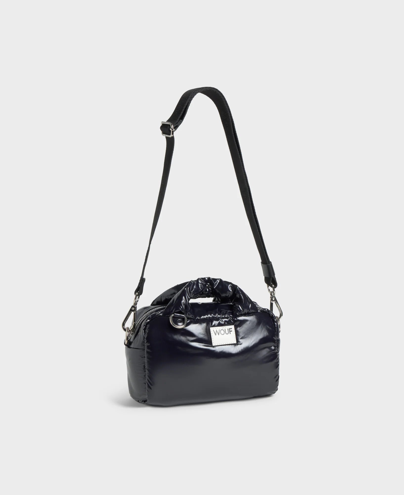 Black handbag with a patent finish on a light gray background