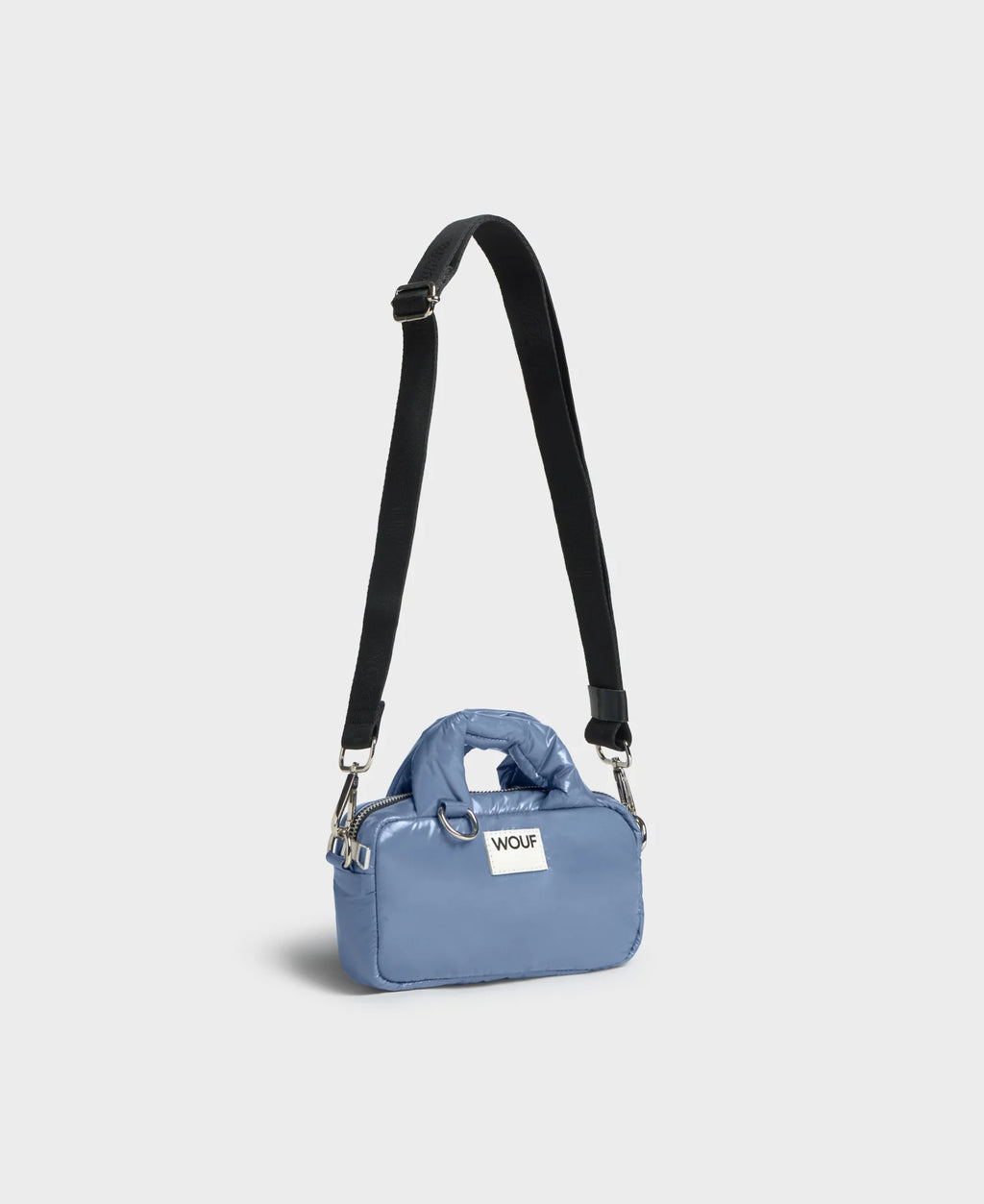 Blue handbag with a black strap on a light gray background