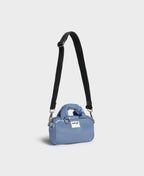 Blue handbag with a black strap on a light gray background