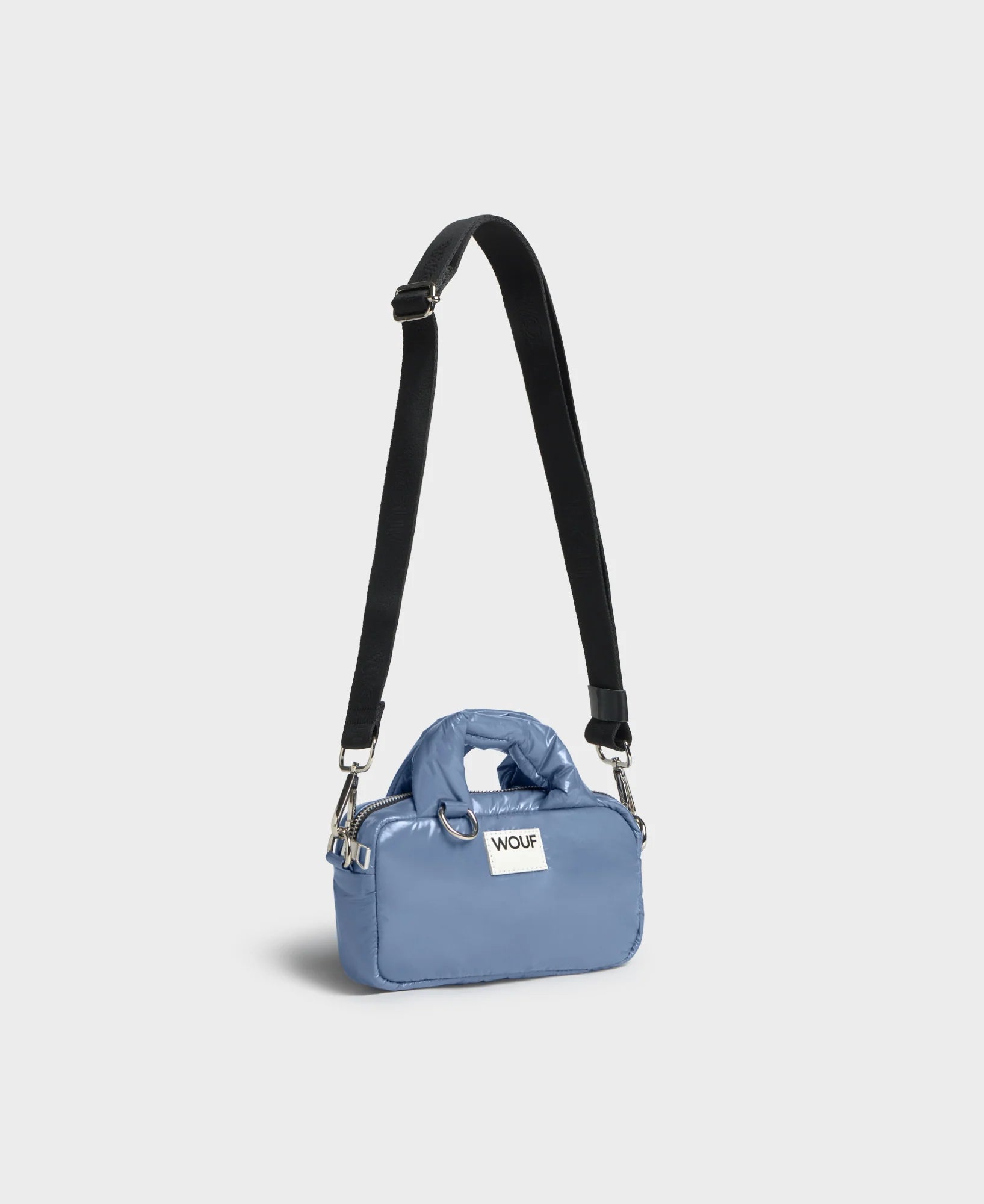 Blue handbag with a black strap on a light gray background