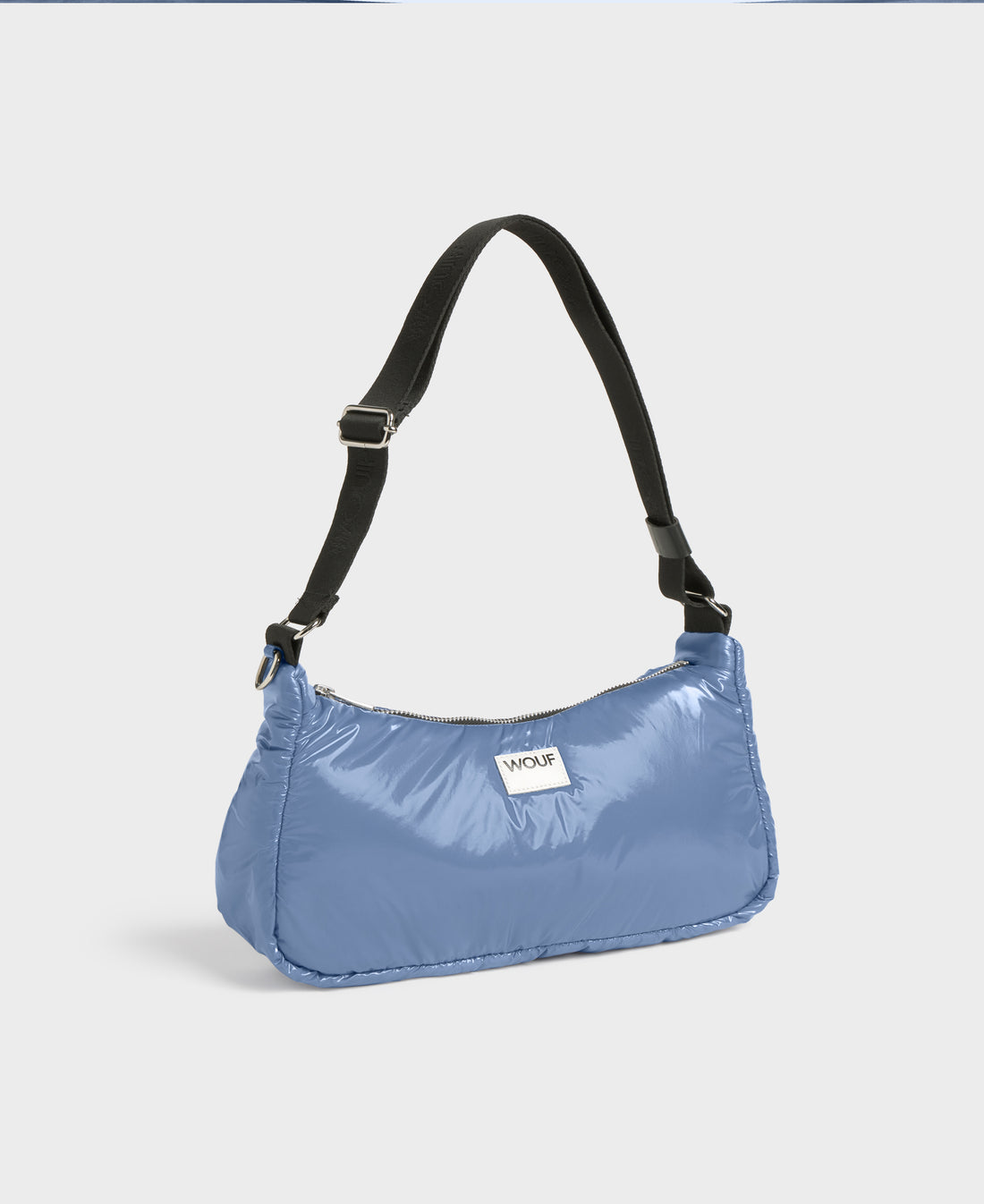 Blue handbag with a black strap on a light gray background
