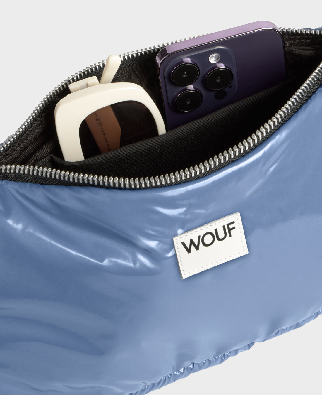 Blue pouch with 'WOUF' brand label containing a phone and other items.