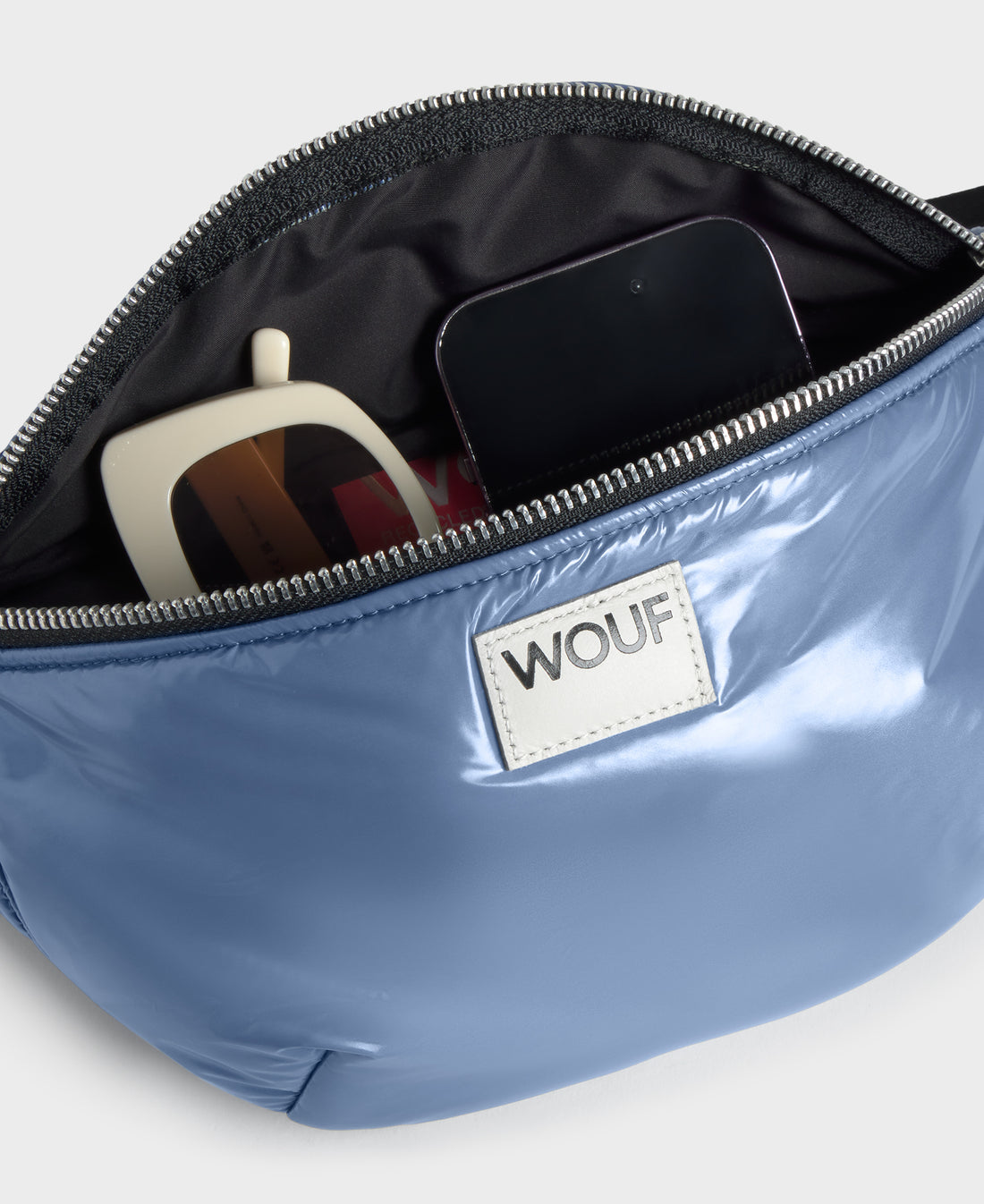 Blue pouch with sunglasses and phone, featuring WOUF brand logo.