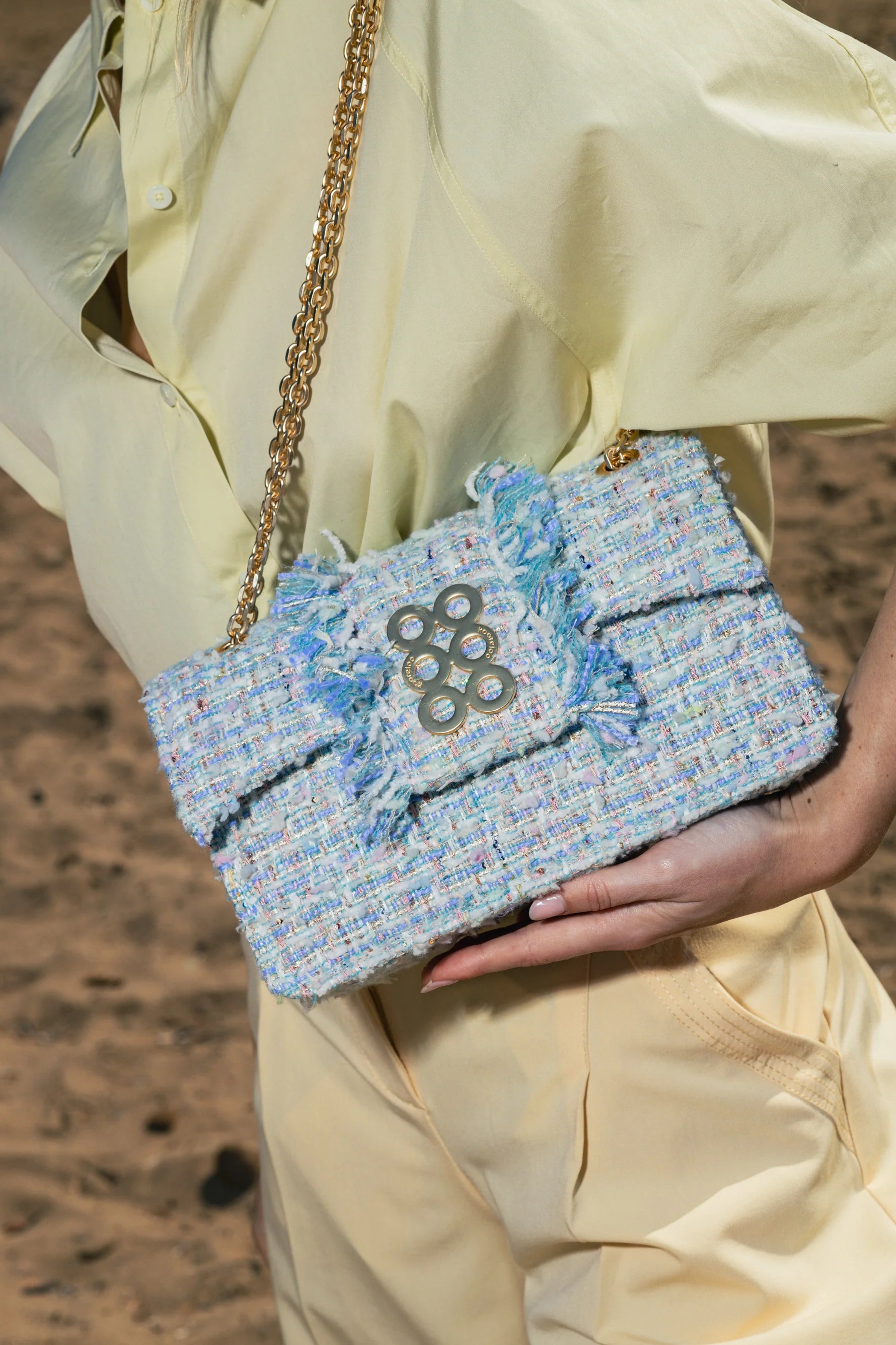 Hand holding a blue and white patterned handbag with a chain strap.